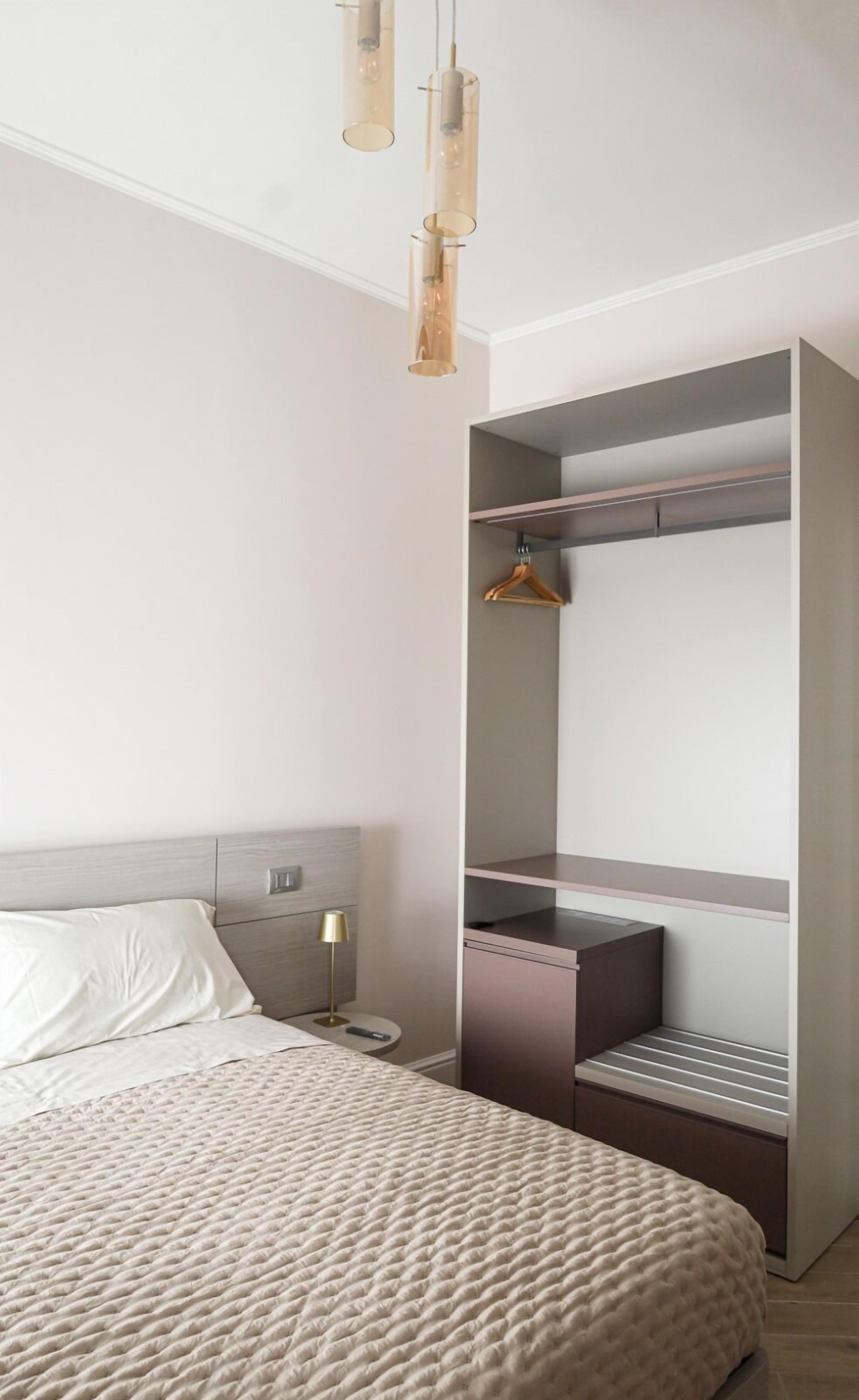 A modern bedroom with a bed, bedside table, lamp, and built-in wardrobe.
