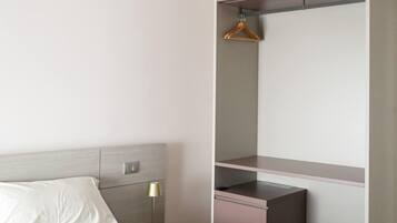 A modern bedroom with a bed, bedside table, lamp, and built-in wardrobe.