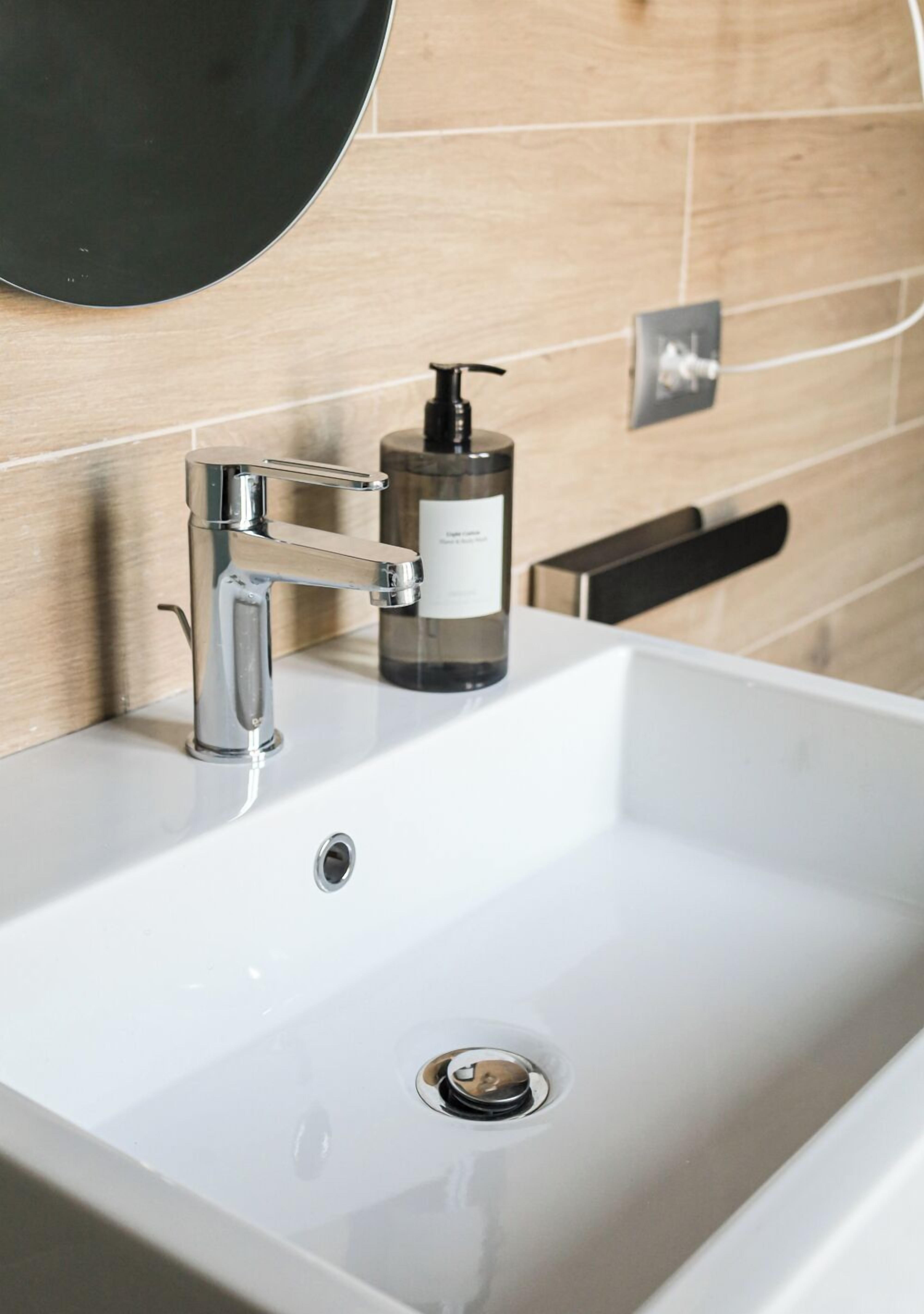 A bathroom sink with a modern faucet, a soap dispenser, and a mirror above it.