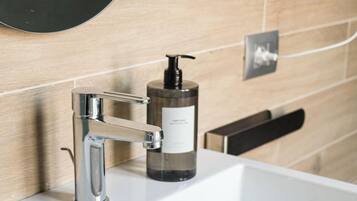 A bathroom sink with a modern faucet, a soap dispenser, and a mirror above it.