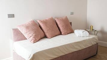Un dormitorio con una cama, una mesita de noche y un enchufe.