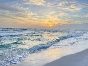 Een strand met golven en een zonsondergang.