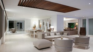 A modern living room with a dining area, featuring a large sectional sofa, round coffee tables, and a wooden ceiling. - Villa Eclipse (Vitet)