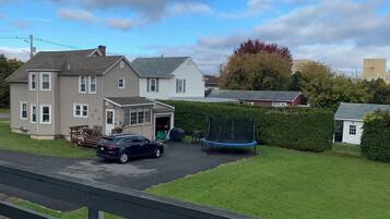 A two-story house with a garage, a trampoline, and a parked car.