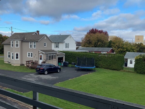 Ein zweistöckiges Haus mit Garage, Trampolin und einem geparkten Auto.