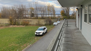 Katettu ulkoalue, jossa on päällystetty kävelyreitti, nurmikko ja rivi parkissa olevia autoja.