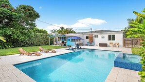 A swimming pool with lounge chairs and a covered patio area.