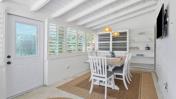 A dining area with a table and chairs, a ceiling fan, and a TV mounted on the wall.