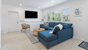 A modern living room with a blue sectional sofa, a wooden coffee table, and a wicker chair.