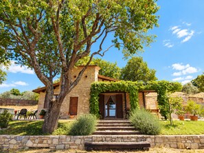 A stone building with a wooden door, surrounded by a stone wall, and a large tree in front. - SCAPPO IN UMBRIA, Le Salce (civitella del lago)