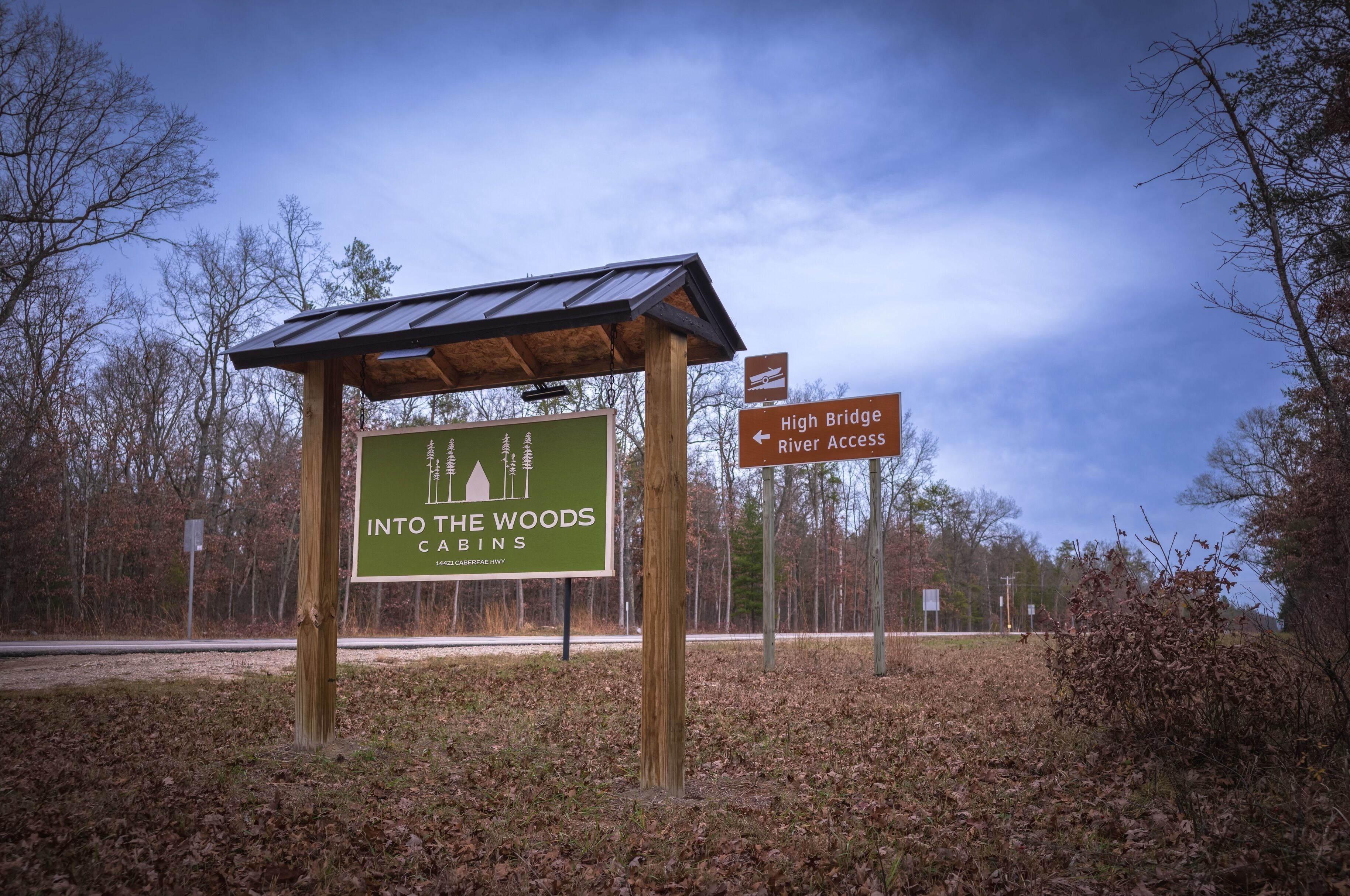 A sign for Into the Woods Cabins with a shelter structure.