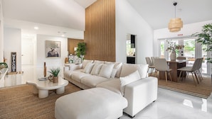 A modern living room with a sectional sofa, a coffee table, and a dining area with chairs and a table.