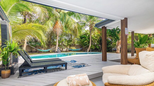 A poolside area with lounge chairs, a small pool, and tropical plants.