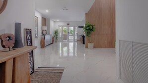 A modern hotel lobby with a polished marble floor, a reception desk, a wooden panel wall, and a potted plant.