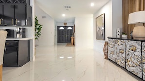 A modern kitchen with stainless steel appliances, a marble floor, and a dining area with a patterned cabinet.