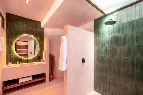 A modern bathroom with a vanity, mirror, and shower. - Casa Yati (Santa María Tonameca)