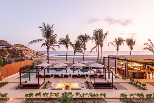 A pool area with lounge chairs, umbrellas, and a bar, overlooking the beach and ocean. - Casa Yati (Santa María Tonameca)