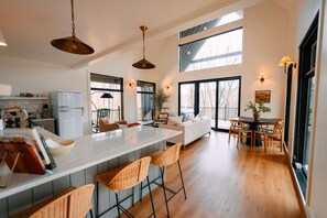 A modern kitchen with a large island, bar stools, and a dining area with a table and chairs.
