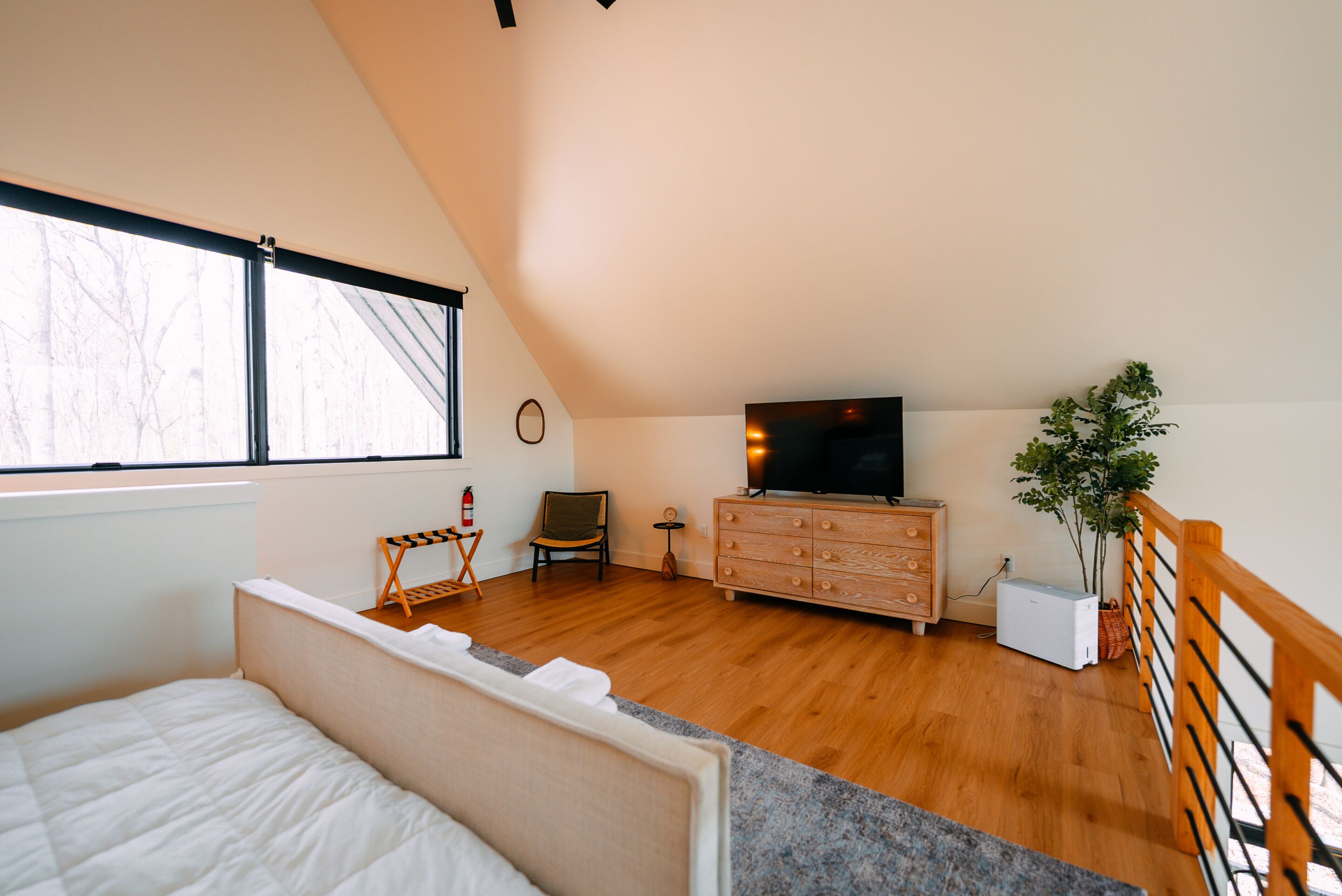 A bedroom with a bed, a dresser, a television, a chair, and a window.