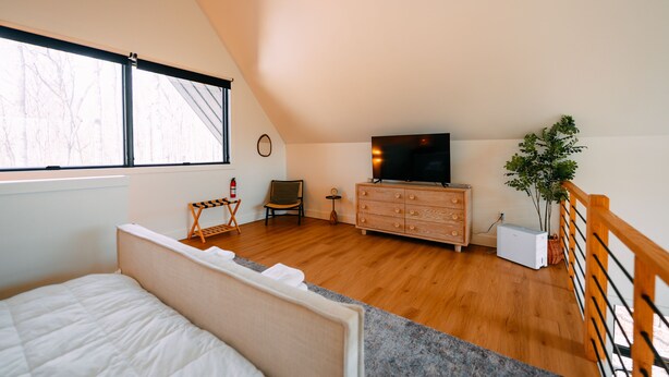 A bedroom with a bed, a dresser, a television, a chair, and a window.