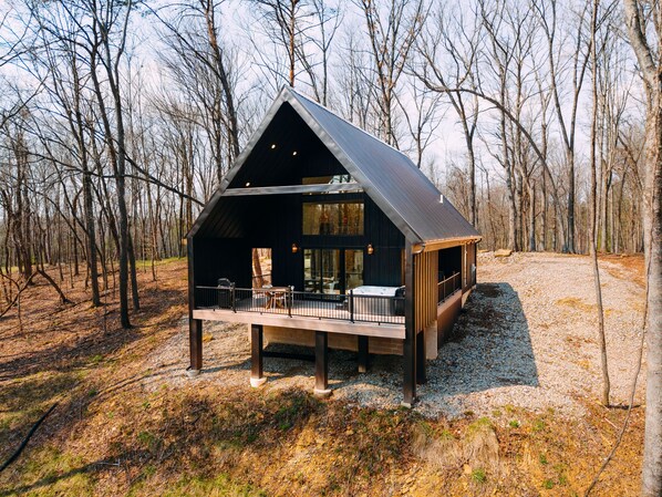 A cabin with a deck, surrounded by trees.