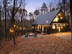 A cabin with a deck, outdoor seating, and string lights. - Stonehaven | Hocking Hills, Modern, Views, Hot Tub (Rockbridge)
