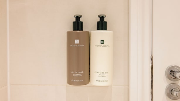 Two bottles of Templespa products, one labeled 'All in Hand' and the other 'Peace Be Still', placed on a tiled surface. - Leicester Square Studios (London)