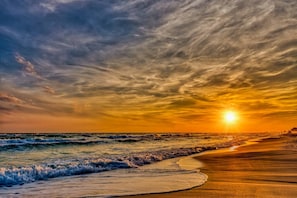 A beach with waves and a sunset.