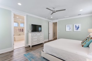 A bedroom with a bed, dresser, television, and artwork on the wall.