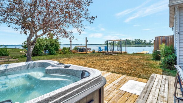Un jardin avec un jacuzzi, une terrasse en bois et une vue sur un lac.
