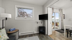 Un salon moderne doté d’une cheminée, d’un téléviseur et offrant une vue sur l’extérieur grâce à une porte-fenêtre coulissante.