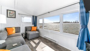 Una cabina con due divani grigi, un tavolino e un'ampia finestra vista acqua.