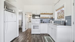 A modern kitchen with white cabinetry, a built-in oven, microwave, and sink.