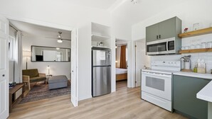 A compact kitchen with a refrigerator, microwave, stove, and a small dining area. - Wellington Cottage at Twin Birch Suites (Prince Edward)