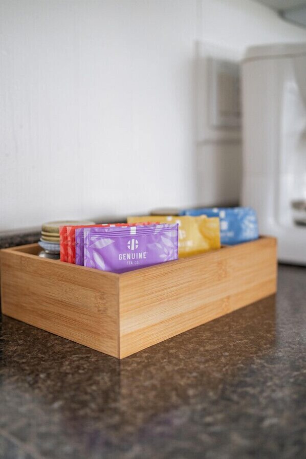 A wooden tray with tea packets on a kitchen counter. - Loyalist Cottage at The Birch (Prince Edward)