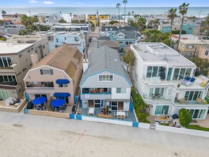 Houses line the beachfront, offering access to the sandy beach.