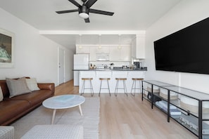 Relax in this open-plan living space with a kitchen area featuring a sofa, coffee table, and flat-screen TV.