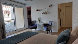 Ett vardagsrum med en soffa, två fåtöljer, ett litet bord och en krukväxt.