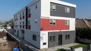 A modern two-story building with a garage door, a flat roof, and a fenced yard. - Urban Retreat USC (Los Angeles)