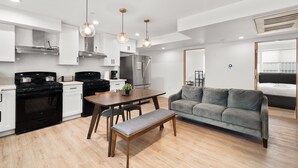 A modern kitchen with white cabinets, black appliances, and pendant lighting. - Urban Retreat USC (Los Angeles)