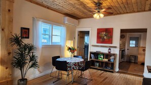 A dining area with a wooden ceiling, a table with chairs, a potted plant, and a window with curtains. - Charming Historic Bungalow (Montrose)