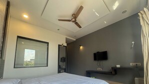 Une chambre moderne avec un lit, un ventilateur de plafond, une télévision et une fenêtre.