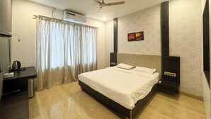 Une chambre d’hôtel moderne dotée d’un grand lit, d’un ventilateur de plafond, d’un climatiseur, d’un bureau avec une bouilloire et de murs à motifs.