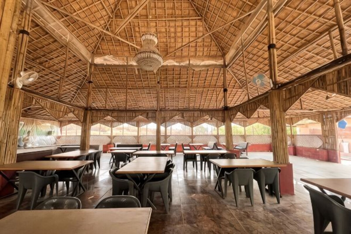 Ett utomhusområde med plats för måltider, inrett med bambustrukturer, bord och stolar.