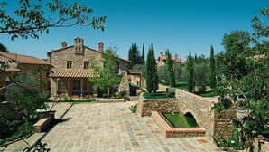 A stone building with a tiled roof, a paved courtyard, and a small water feature.