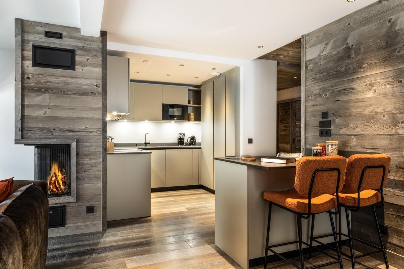 Een moderne keuken met een centraal eiland, inbouwapparatuur en een open haard.