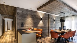 Une cuisine moderne agrémentée d’éléments en bois, un coin repas avec des chaises orange et un bar.