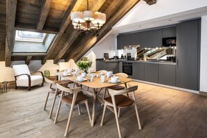 A modern loft-style room with a dining area, kitchen, and skylight.