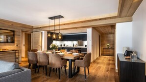 A modern kitchen with wooden accents, a dining area with a wooden table and chairs, and a cozy seating area with a grey sofa. - Wifi, 150m from ski slopes, 1st floor, view mountain, sauna, hammam, balcony, fireplace or stove, tv (Méribel - Les Allues)