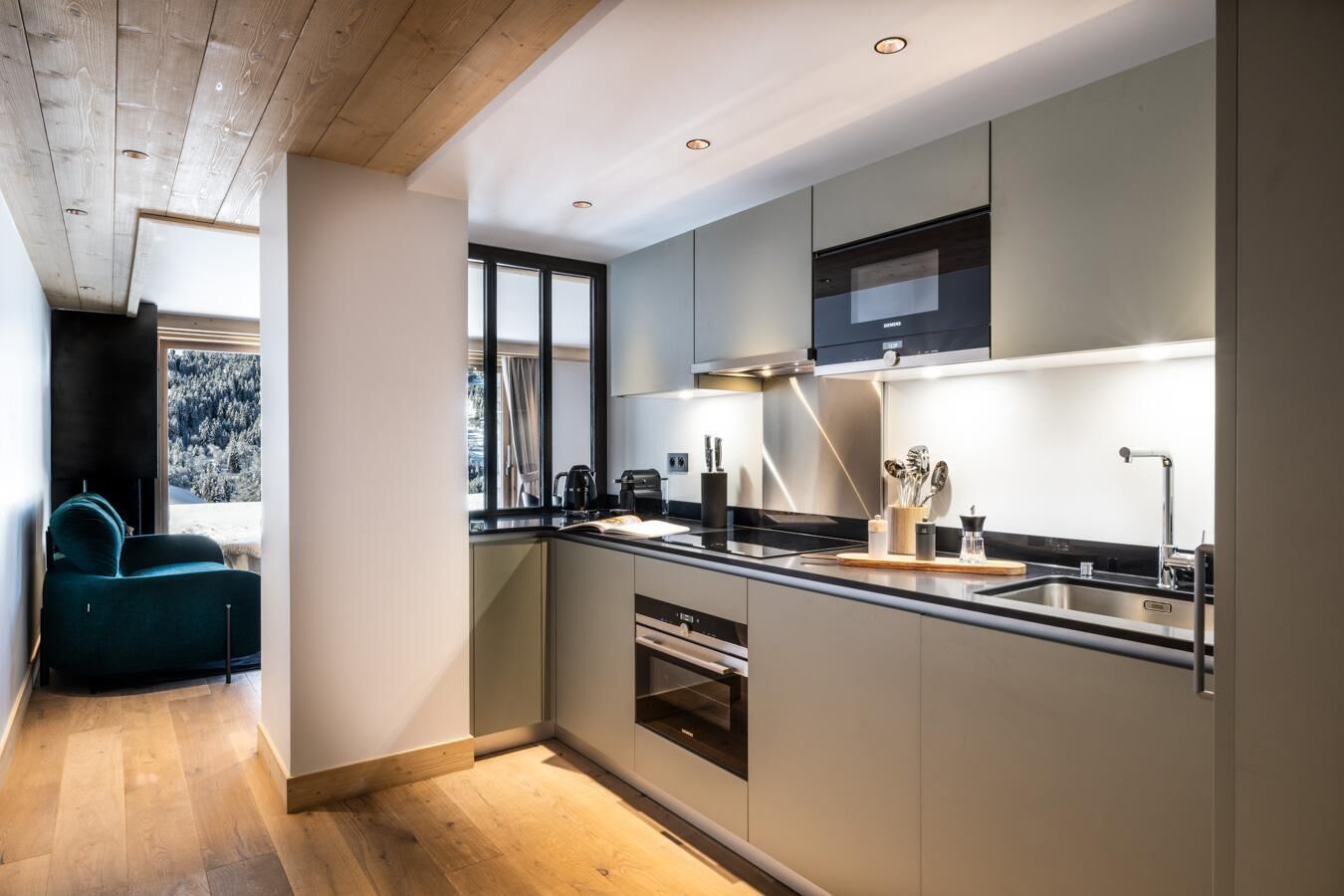 Een moderne keuken met een groot raam, inbouwapparatuur en een gezellige zithoek.